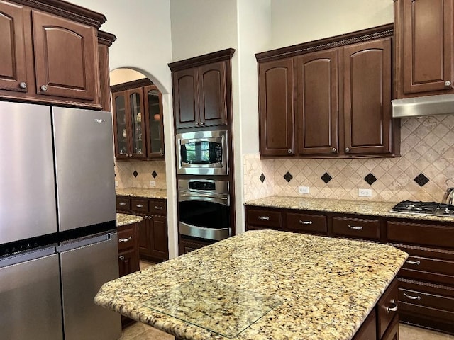 13839 Oak Fair Bnd, Cypress, TX 77429 - kitchen featuring appliances with stainless steel finishes, dark brown cabinets, tasteful backsplash, and light stone counters