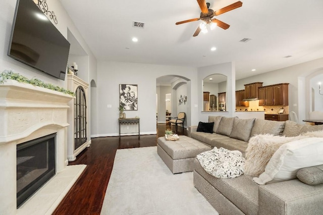 13839 Oak Fair Bnd, Cypress, TX 77429 - living room featuring arched walkways, a ceiling fan, a glass covered fireplace, wood finished floors, and recessed lighting