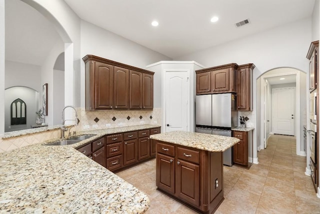 13839 Oak Fair Bnd, Cypress, TX 77429 - kitchen featuring freestanding refrigerator, tasteful backsplash, arched walkways, light stone counters, and recessed lighting