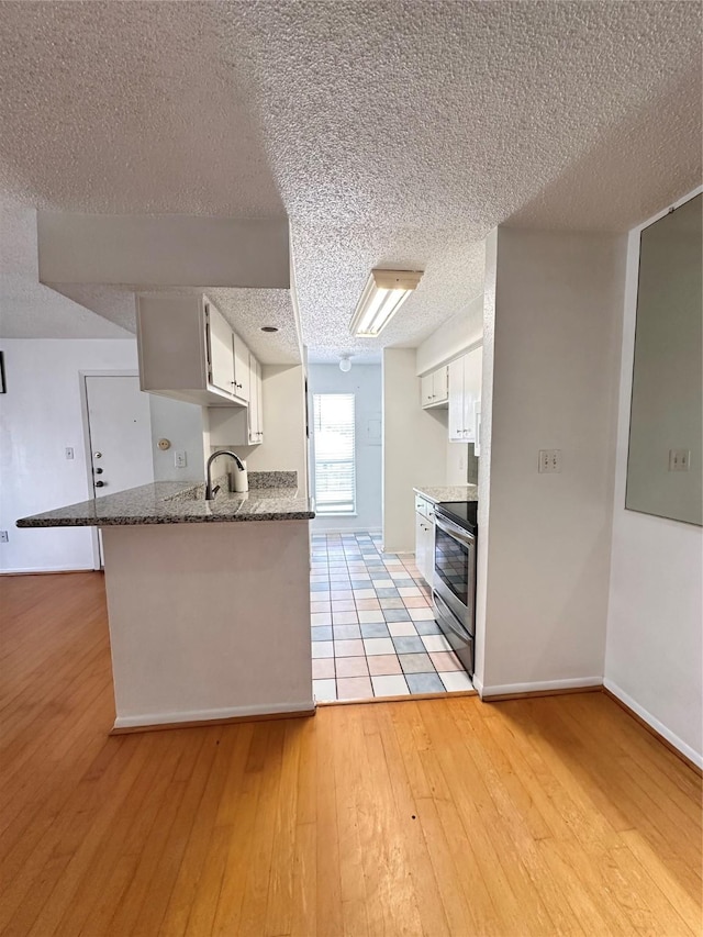 260 El Dorado Blvd Unit 2608, Houston, TX 77598 - kitchen featuring stainless steel electric range oven, a textured ceiling, a peninsula, light wood finished floors, and white cabinets