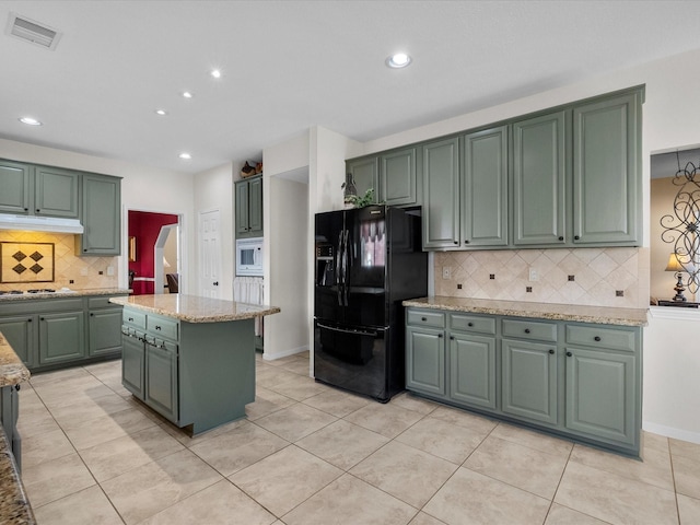 1410 Juniper Ln, Seabrook, TX 77586 - kitchen with black fridge with ice dispenser, green cabinetry, white microwave, decorative backsplash, and light stone counters