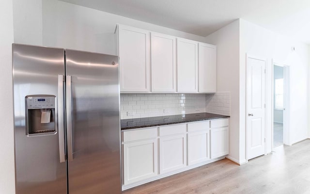 25035 Apricot Ct, Montgomery, TX 77316 - kitchen with stainless steel fridge, light wood-type flooring, dark stone countertops, white cabinets, and decorative backsplash