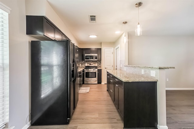10327 Collingswood Rd, La Porte, TX 77571 - kitchen featuring appliances with stainless steel finishes, light wood-style floors, tasteful backsplash, light stone counters, and decorative light fixtures