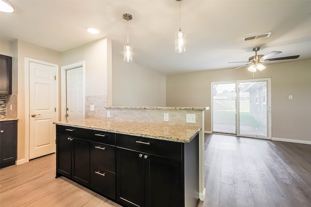 10327 Collingswood Rd, La Porte, TX 77571 - kitchen featuring dark cabinetry, tasteful backsplash, light wood-style flooring, a ceiling fan, and light stone countertops