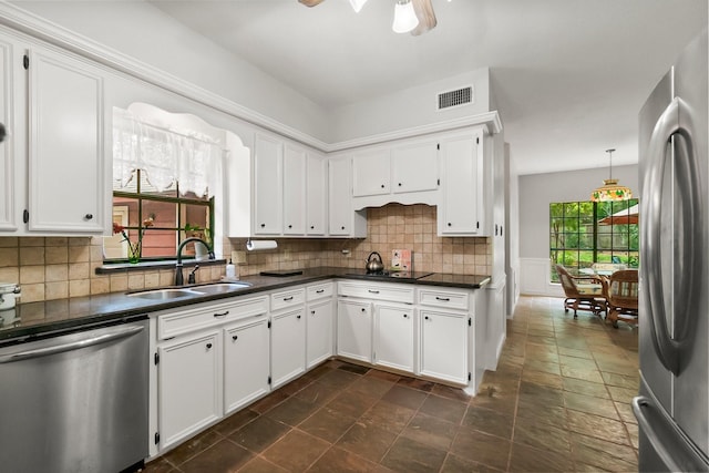 5 Hartwick Ct, Conroe, TX 77304 - kitchen with appliances with stainless steel finishes, dark countertops, white cabinets, ceiling fan, and decorative backsplash