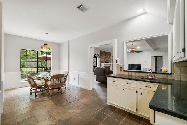 5 Hartwick Ct, Conroe, TX 77304 - dining room with ceiling fan, a decorative wall, wainscoting, stone tile floors, and a fireplace