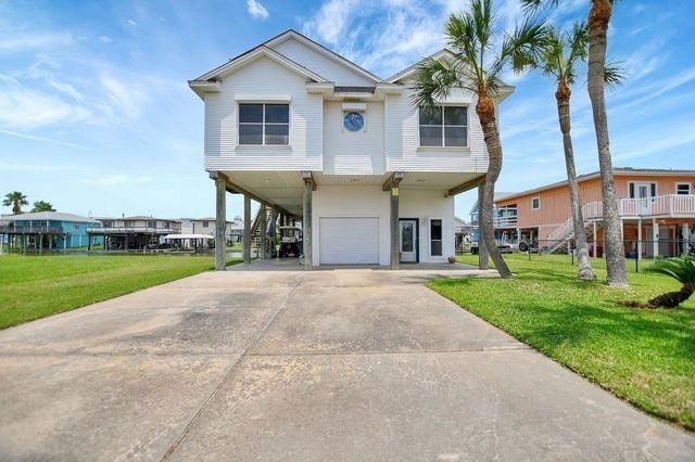 23002 Lunes St, Galveston, TX 77554 - coastal home featuring a carport, stairs, a garage, a front lawn, and concrete driveway