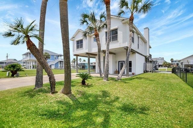 23002 Lunes St, Galveston, TX 77554 - rear view of house featuring a carport, a residential view, driveway, and a chimney
