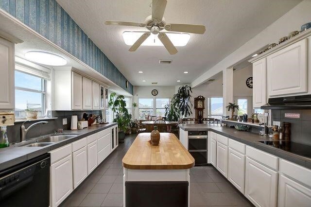 23002 Lunes St, Galveston, TX 77554 - kitchen featuring black appliances, dark tile patterned floors, ceiling fan, under cabinet range hood, and wallpapered walls
