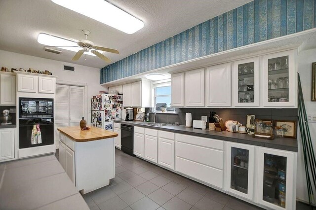 23002 Lunes St, Galveston, TX 77554 - kitchen featuring black appliances, wallpapered walls, a ceiling fan, white cabinetry, and dark tile patterned floors