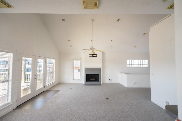 23002 Lunes St, Galveston, TX 77554 - unfurnished living room featuring carpet flooring, a fireplace with flush hearth, french doors, high vaulted ceiling, and a ceiling fan