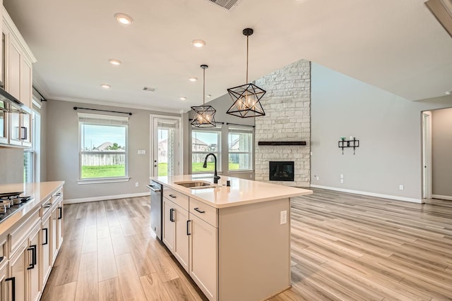 2008 Bristol Cliff Ln, Pearland, TX 77089 - kitchen with light wood-style floors, a stone fireplace, light countertops, a center island with sink, and open floor plan