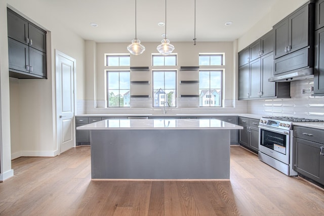 1716 Sedola Ln, Houston, TX 77055 - kitchen featuring stainless steel range with gas cooktop, backsplash, under cabinet range hood, light countertops, and light wood-style flooring