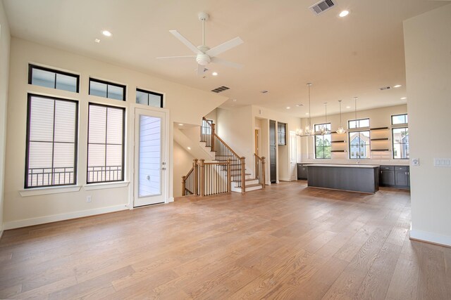 1716 Sedola Ln, Houston, TX 77055 - unfurnished living room featuring light wood-style floors, stairway, recessed lighting, a ceiling fan, and a chandelier