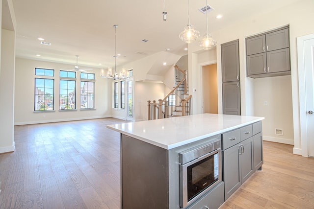 1716 Sedola Ln, Houston, TX 77055 - kitchen featuring gray cabinets, stainless steel microwave, recessed lighting, light wood-type flooring, and a center island