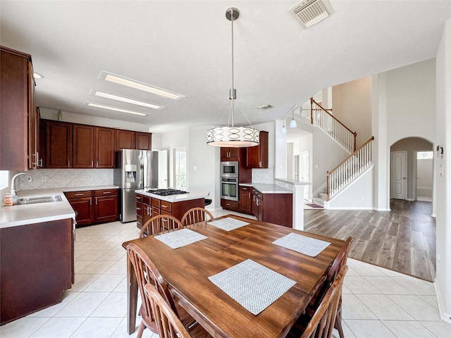 3106 Alexandros Ct, Pearland, TX 77584 - dining space featuring arched walkways, stairs, and light tile patterned flooring