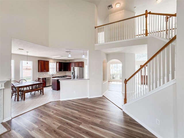 3106 Alexandros Ct, Pearland, TX 77584 - living room featuring a towering ceiling, arched walkways, plenty of natural light, light wood-style flooring, and stairway
