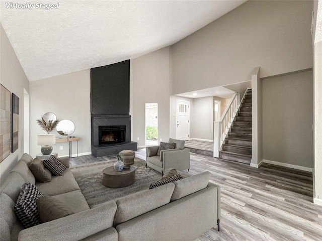 10610 Mills Prairie St, Houston, TX 77070 - living room featuring wood finished floors, high vaulted ceiling, stairway, and a large fireplace