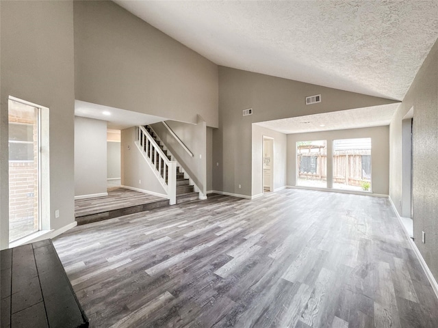 10610 Mills Prairie St, Houston, TX 77070 - unfurnished living room with stairs, wood finished floors, high vaulted ceiling, and a textured ceiling