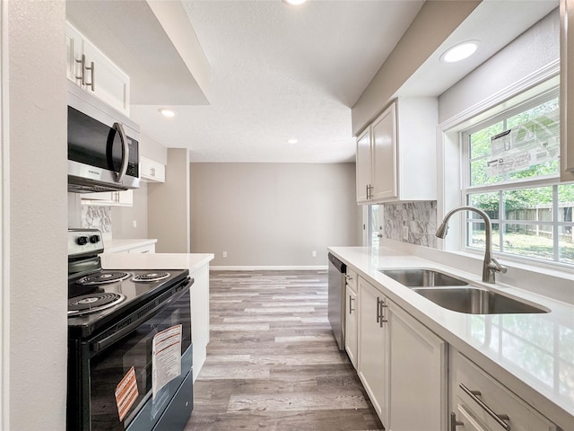 10610 Mills Prairie St, Houston, TX 77070 - kitchen featuring appliances with stainless steel finishes, backsplash, light countertops, light wood-style flooring, and white cabinetry