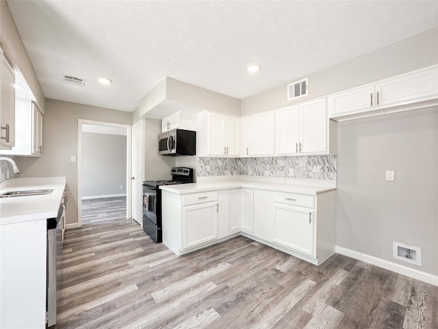 10610 Mills Prairie St, Houston, TX 77070 - kitchen with range with electric cooktop, stainless steel microwave, light wood-type flooring, white cabinets, and recessed lighting