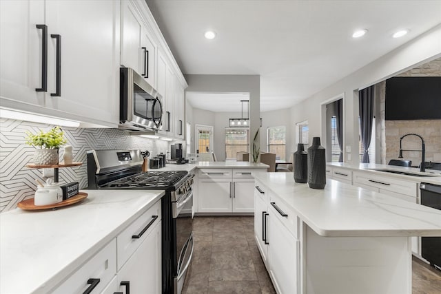 4318 Raintree Ct, Pasadena, TX 77505 - kitchen featuring stainless steel appliances, decorative backsplash, white cabinets, a peninsula, and a center island