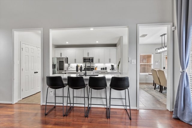 4318 Raintree Ct, Pasadena, TX 77505 - kitchen with appliances with stainless steel finishes, a kitchen breakfast bar, light countertops, white cabinets, and recessed lighting