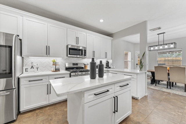 4318 Raintree Ct, Pasadena, TX 77505 - kitchen featuring stainless steel appliances, tasteful backsplash, white cabinets, decorative light fixtures, and a center island