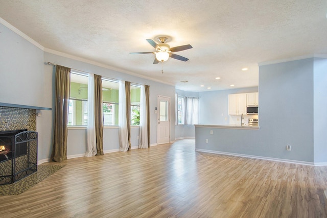 8806 Aberdeen Oaks Dr, Houston, TX 77095 - unfurnished living room with light wood-style floors, a ceiling fan, a textured ceiling, ornamental molding, and a tiled fireplace
