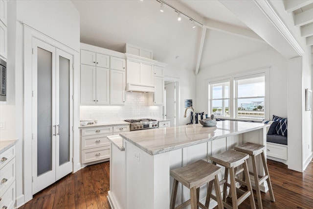 4107 Bluewing Teal Ct, Galveston, TX 77554 - kitchen with white cabinetry, dark wood-type flooring, tasteful backsplash, light stone countertops, and a kitchen breakfast bar