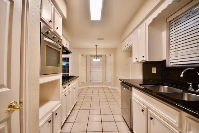 18723 Clover Gln, Katy, TX 77084 - kitchen with stainless steel appliances, light tile patterned floors, white cabinetry, decorative light fixtures, and dark countertops