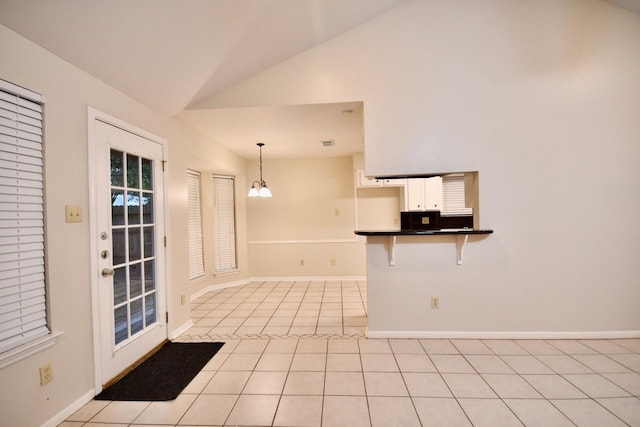 18723 Clover Gln, Katy, TX 77084 - kitchen with a breakfast bar, dark countertops, white cabinetry, light tile patterned floors, and vaulted ceiling