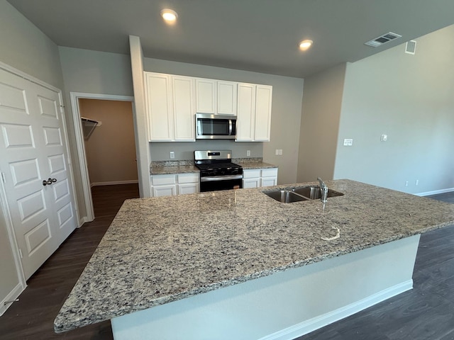 2572 Hawks Eye Dr, Conroe, TX 77301 - kitchen with range with gas cooktop, stainless steel microwave, white cabinets, dark wood-style flooring, and a center island with sink