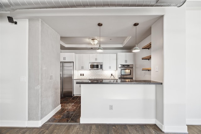 1901 Post Oak Blvd Unit 609, Houston, TX 77056 - kitchen featuring appliances with stainless steel finishes, a tray ceiling, white cabinetry, a peninsula, and backsplash