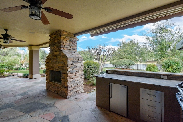 42 Lake Sterling Gate Dr, Spring, TX 77379 - view of patio with an outdoor stone fireplace, a ceiling fan, and an outdoor kitchen
