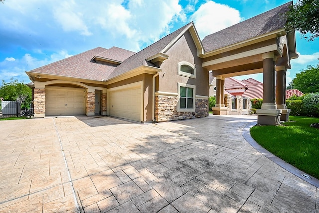 42 Lake Sterling Gate Dr, Spring, TX 77379 - view of front of home with an attached garage, stone siding, decorative driveway, stucco siding, and roof with shingles