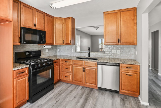 3445 Van Ness Dr, Alvin, TX 77511 - kitchen featuring black appliances, light wood-type flooring, decorative backsplash, light stone countertops, and brown cabinetry