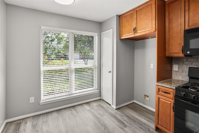 3445 Van Ness Dr, Alvin, TX 77511 - kitchen featuring black appliances, light wood finished floors, brown cabinetry, backsplash, and stone countertops