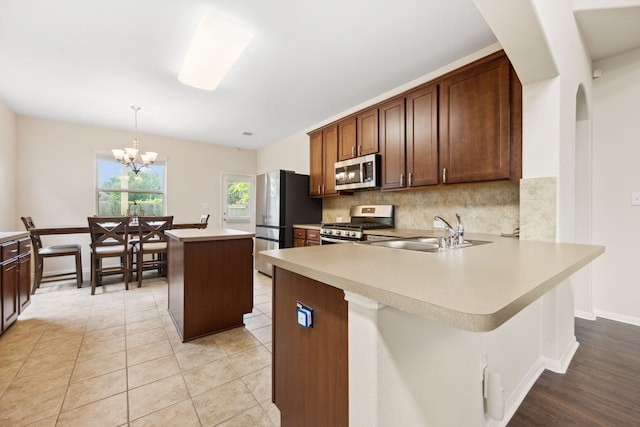 11134 Sun River Falls Dr, Humble, TX 77396 - kitchen featuring appliances with stainless steel finishes, decorative backsplash, light countertops, a kitchen island, and a chandelier