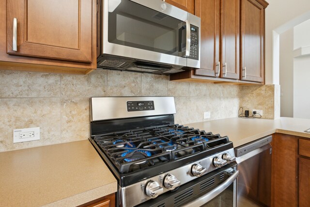 11134 Sun River Falls Dr, Humble, TX 77396 - kitchen with stainless steel appliances, light countertops, brown cabinetry, and decorative backsplash