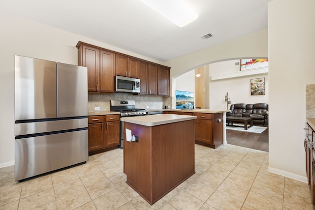11134 Sun River Falls Dr, Humble, TX 77396 - kitchen with appliances with stainless steel finishes, arched walkways, light countertops, a center island, and light tile patterned floors