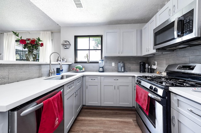 18446 N Willow Bluff Rd, Katy, TX 77449 - kitchen with appliances with stainless steel finishes, a textured ceiling, light countertops, tasteful backsplash, and wood finished floors