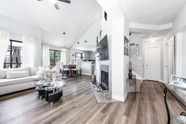 18446 N Willow Bluff Rd, Katy, TX 77449 - living area with wood finished floors, a ceiling fan, lofted ceiling, and a fireplace with flush hearth