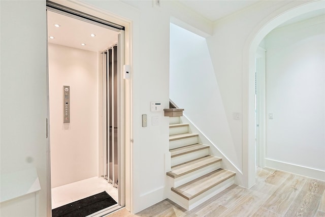 2425 E Seaside Dr, Galveston, TX 77550 - stairs featuring elevator, wood finished floors, arched walkways, and recessed lighting