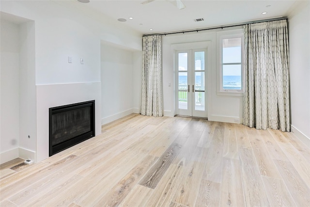 2425 E Seaside Dr, Galveston, TX 77550 - unfurnished living room featuring wood finished floors, a glass covered fireplace, recessed lighting, and french doors