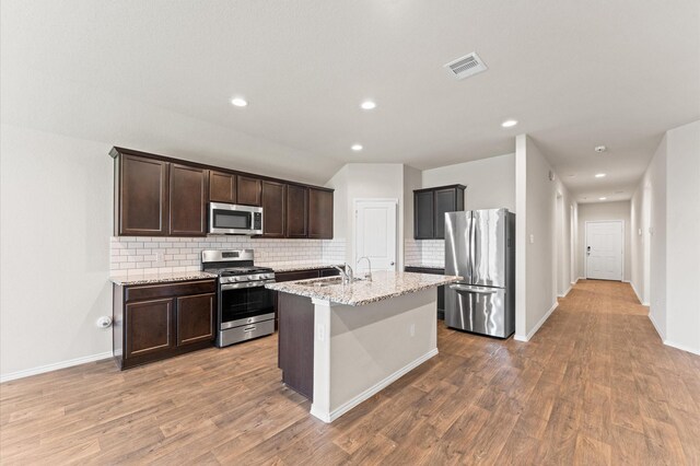 919 Bright Lotus Ln, Rosharon, TX 77583 - kitchen with stainless steel appliances, backsplash, dark brown cabinetry, wood finished floors, and recessed lighting