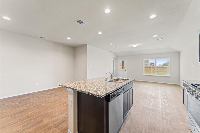 919 Bright Lotus Ln, Rosharon, TX 77583 - kitchen featuring appliances with stainless steel finishes, open floor plan, light wood-type flooring, a kitchen island with sink, and recessed lighting