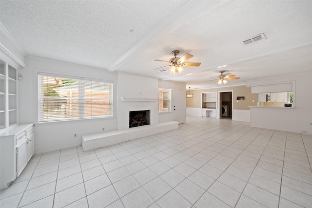 19011 Oakway Dr, Spring, TX 77388 - unfurnished living room featuring a textured ceiling, a brick fireplace, a ceiling fan, light tile patterned floors, and washer / clothes dryer