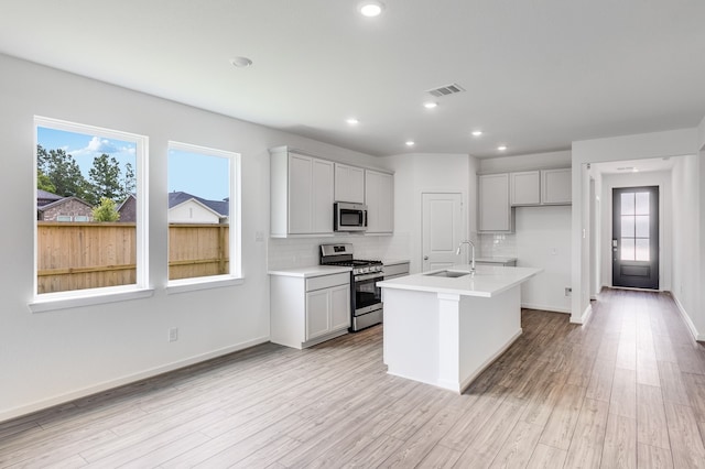 1235 Buffalo Run, Tomball, TX 77375 - kitchen featuring appliances with stainless steel finishes, decorative backsplash, healthy amount of natural light, a kitchen island with sink, and recessed lighting