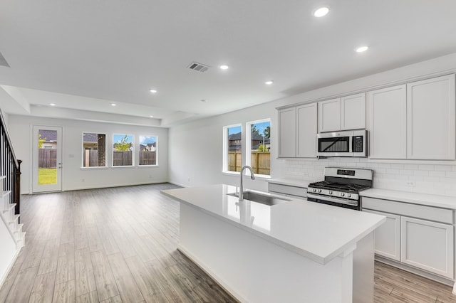 1235 Buffalo Run, Tomball, TX 77375 - kitchen featuring stainless steel appliances, a kitchen island with sink, light countertops, backsplash, and open floor plan